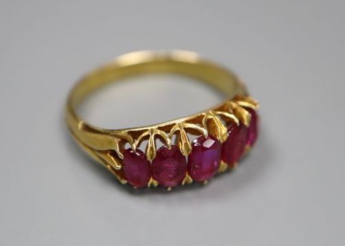 A yellow metal and graduated five stone ruby set half hoop ring,